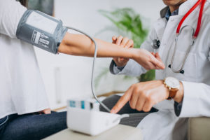 Young Male Psysician With Patient Measuring Blood Pressure